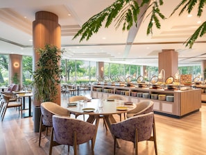A modern dining area with round tables, chairs, and a central buffet with various dishes. - Mercure Nagano Matsushiro Resort & Spa (Nagano)