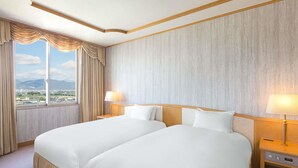 A hotel room with two beds, a large window with curtains, and a view of a cityscape.