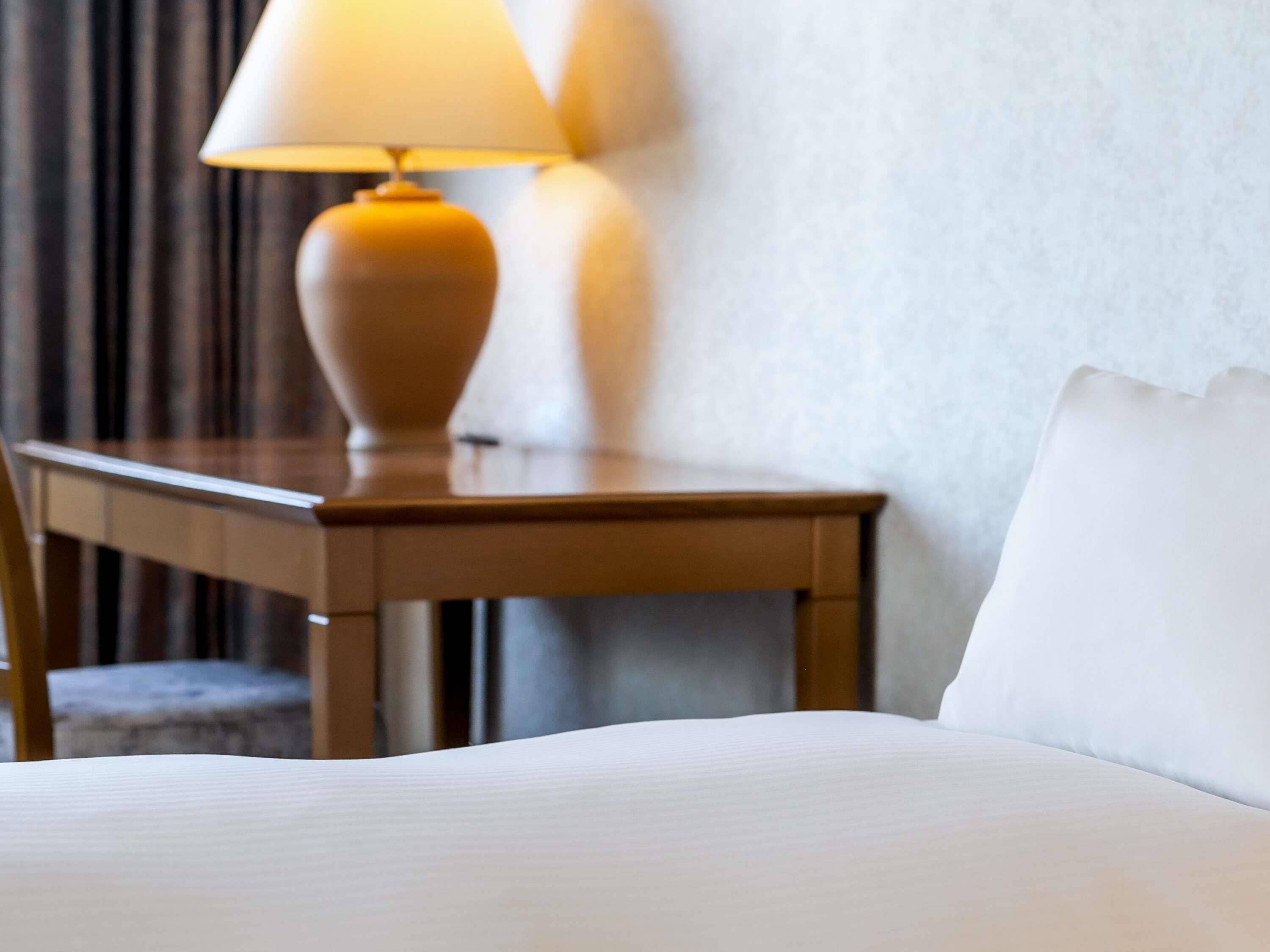 Ein Hotelzimmer mit einem Bett, einem Nachttisch aus Holz und einer Lampe.