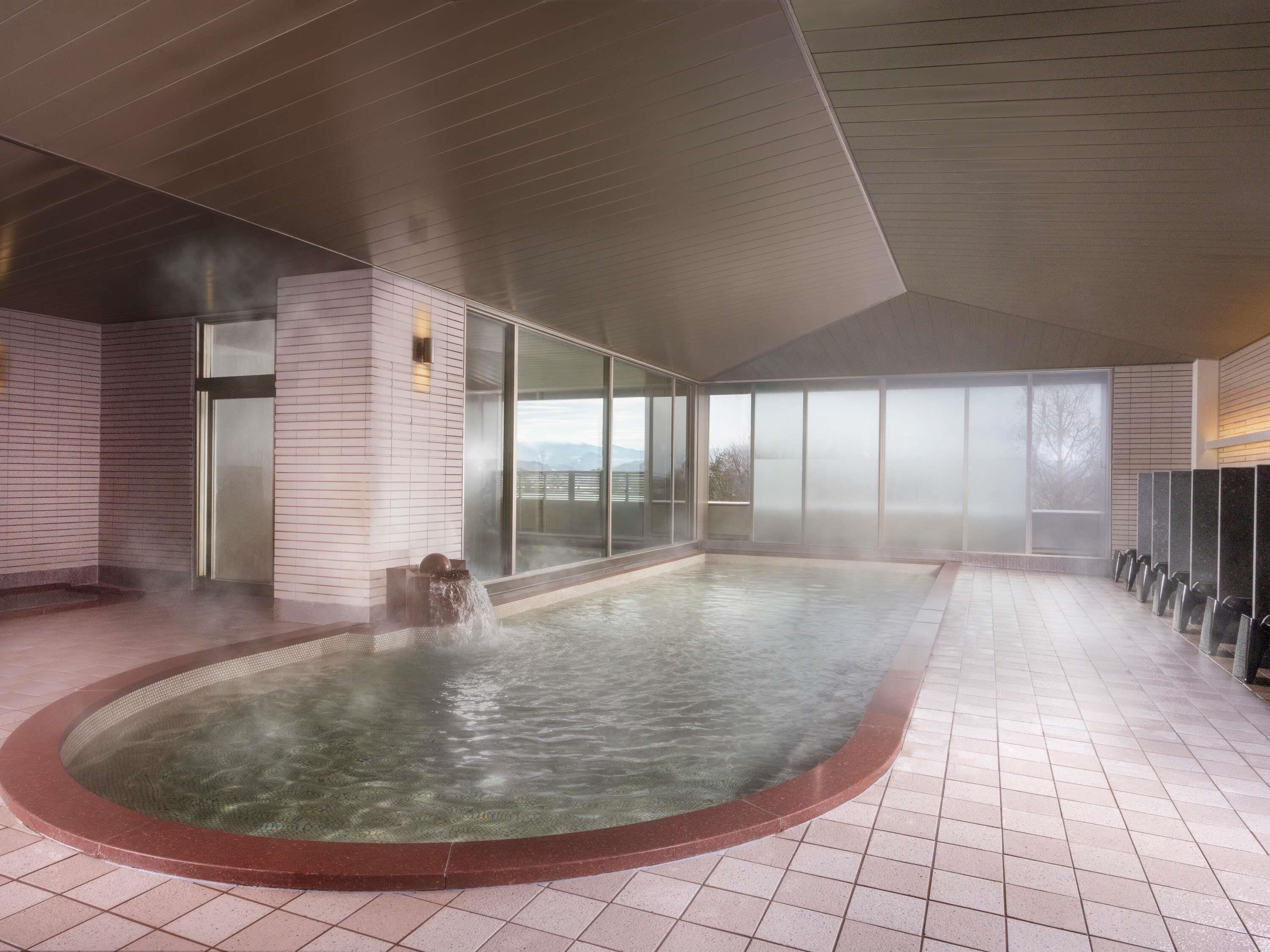 Piscina interior moderna con función de vapor, ventanas amplias y suelo de baldosas.