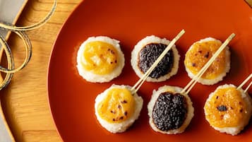 Een bord met vijf sushi stukken, elk met een andere topping, op een houten tafel.