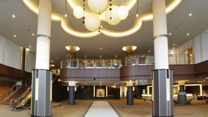 A spacious lobby with a central circular light fixture, multiple floors, and a staircase.