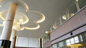 A modern interior with a high ceiling, large cylindrical light fixtures, and a multi-level structure with glass railings.