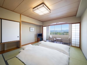 Ein Hotelzimmer mit Tatami-Matten, einem Bett, einem Fernseher, einem Schreibtisch und Bergblick.