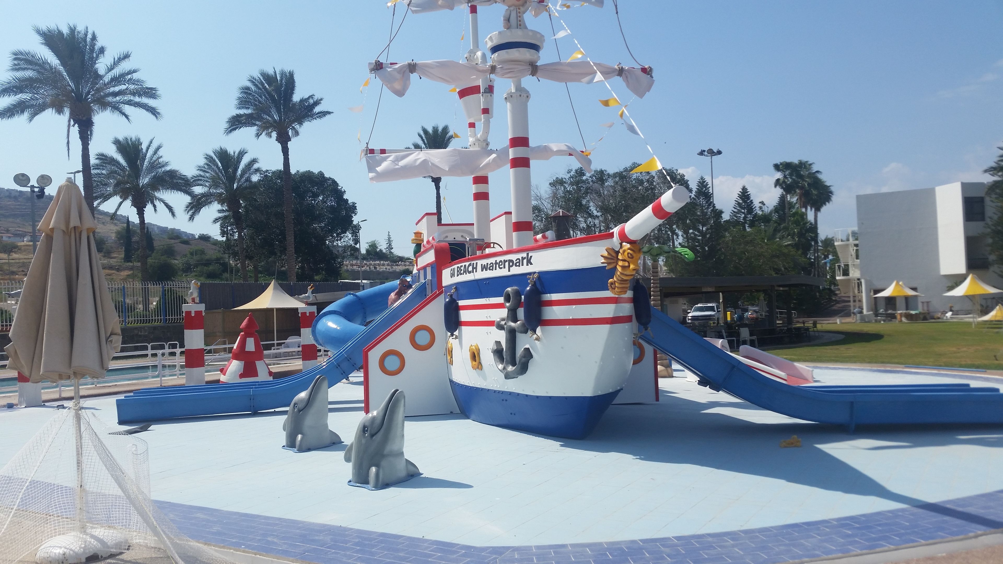A waterpark with a ship-themed play area, including slides and dolphin-shaped structures.