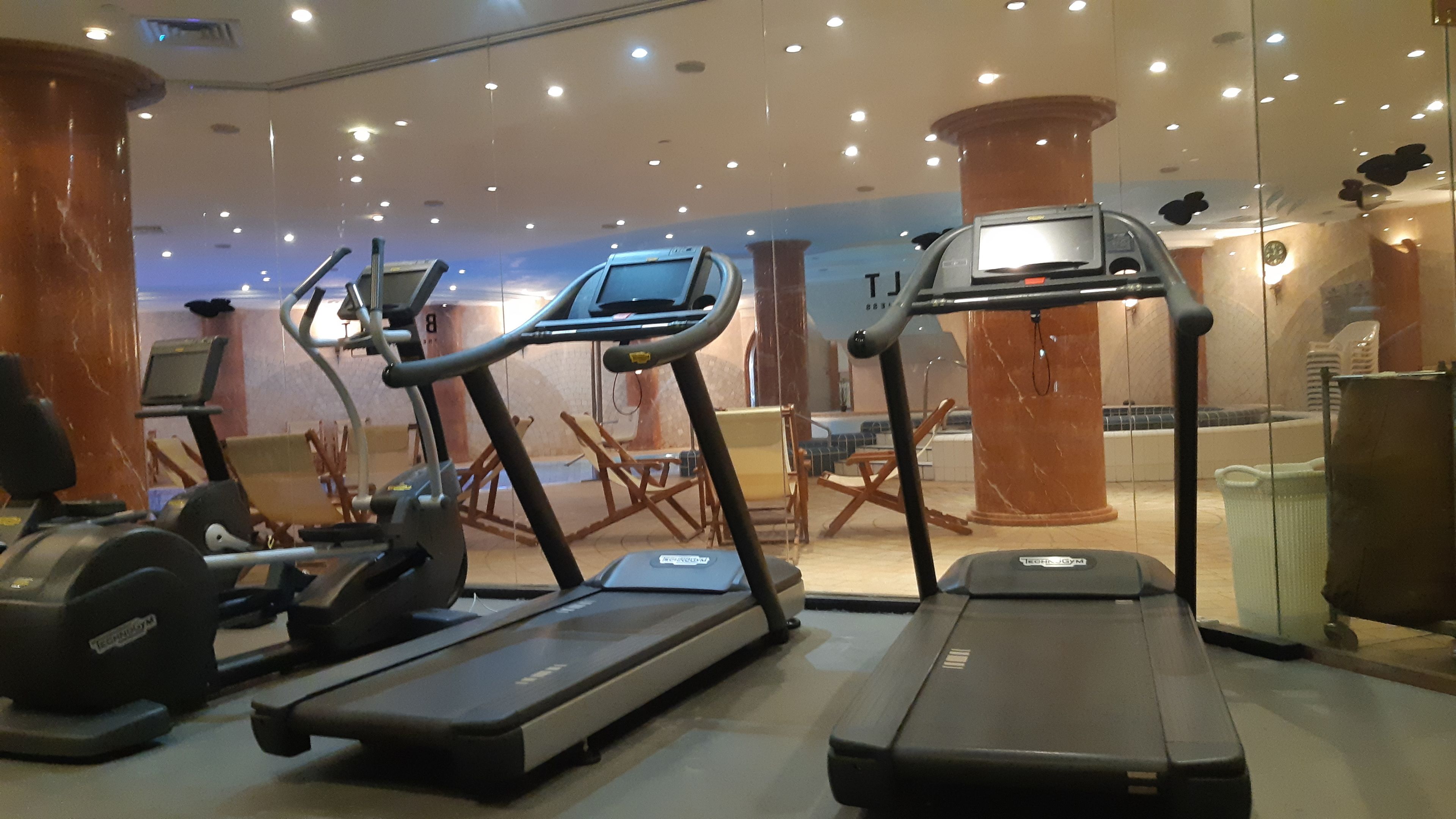 Un gimnasio con cintas de correr, bicicletas estáticas y una máquina de pesas.