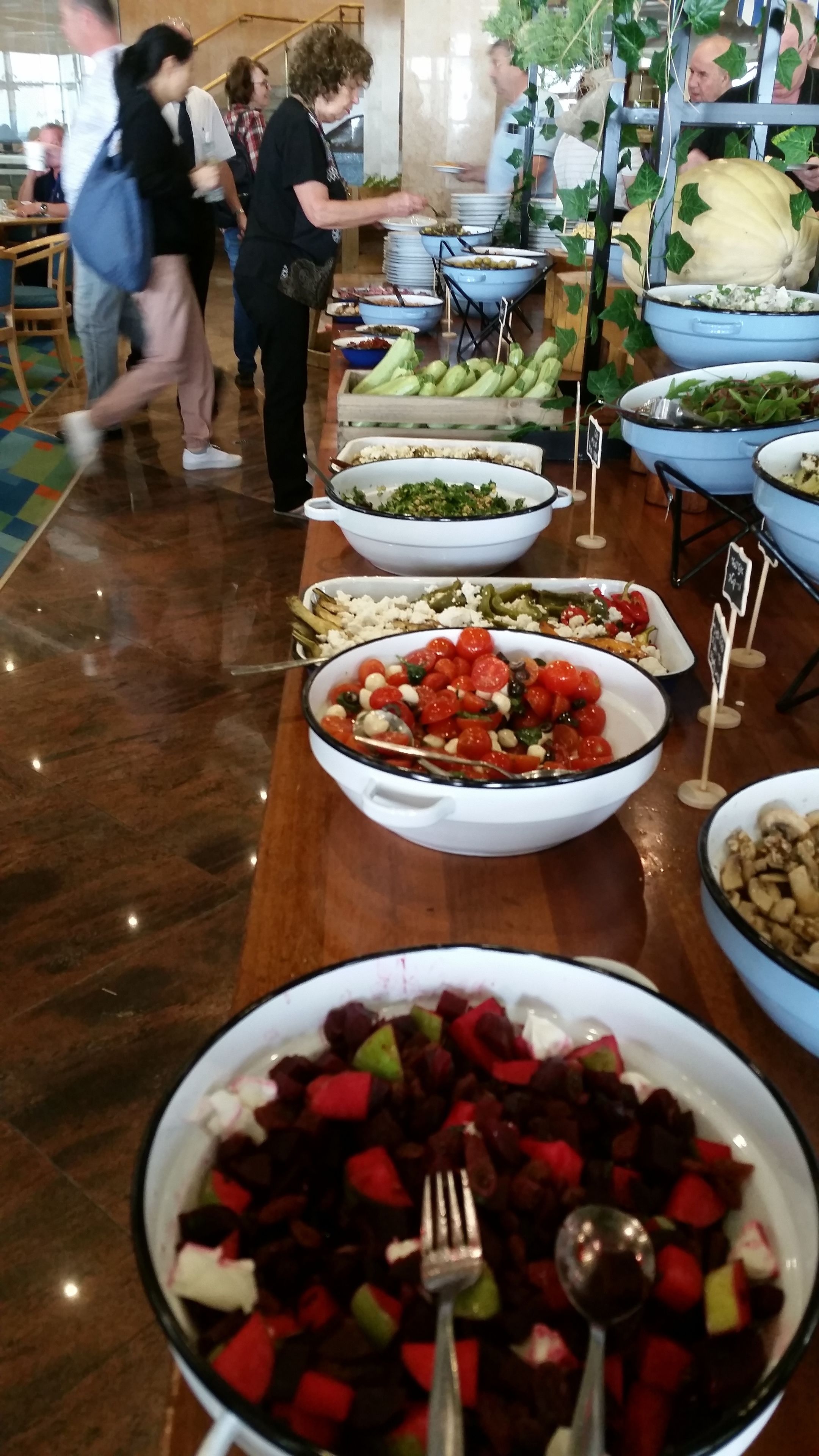 A buffet with various dishes including salads, fruits, and vegetables.
