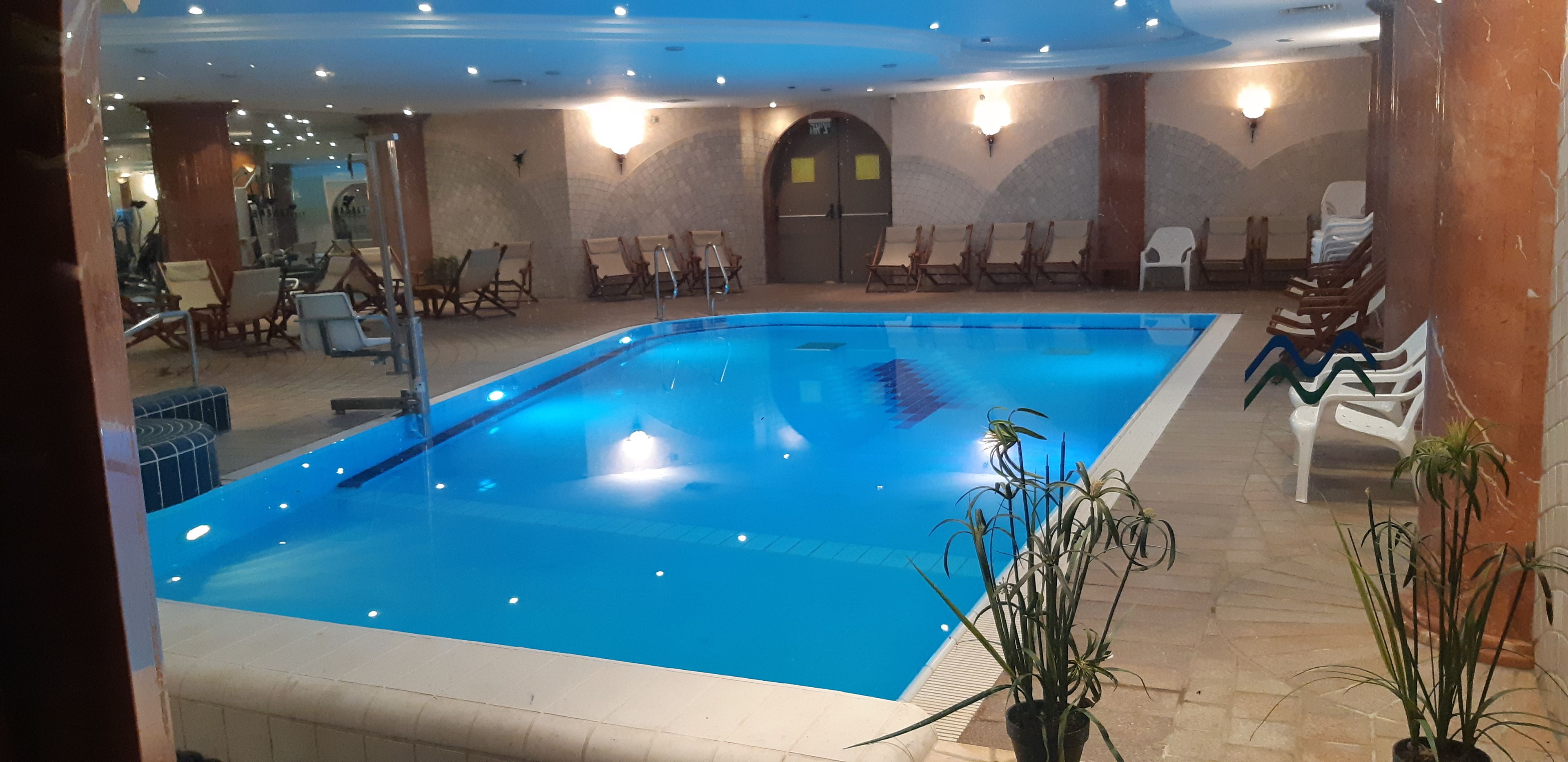 A swimming pool with lounge chairs and potted plants.