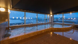 A modern indoor pool with a view of a cityscape at dusk. - Hida Hotel Plaza (Takayama)