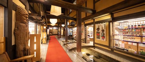 A traditional Japanese inn with a red carpet, wooden beams, and a koi pond.