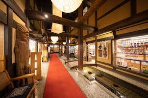 Una posada japonesa tradicional con alfombra roja, vigas de madera y un estanque de peces koi.