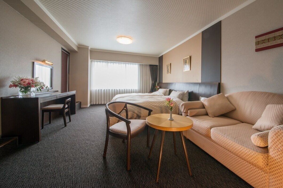 Ein Hotelzimmer mit Bett, Sofa, Schreibtisch, Stuhl und einem kleinen Tisch.