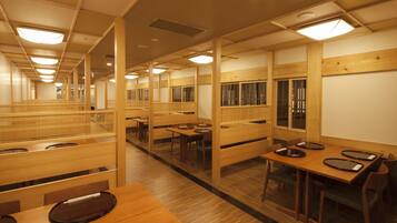 Ein traditionelles japanisches Restaurant mit Holzeinrichtung, mehreren Essplätzen und einem zentralen Gang.