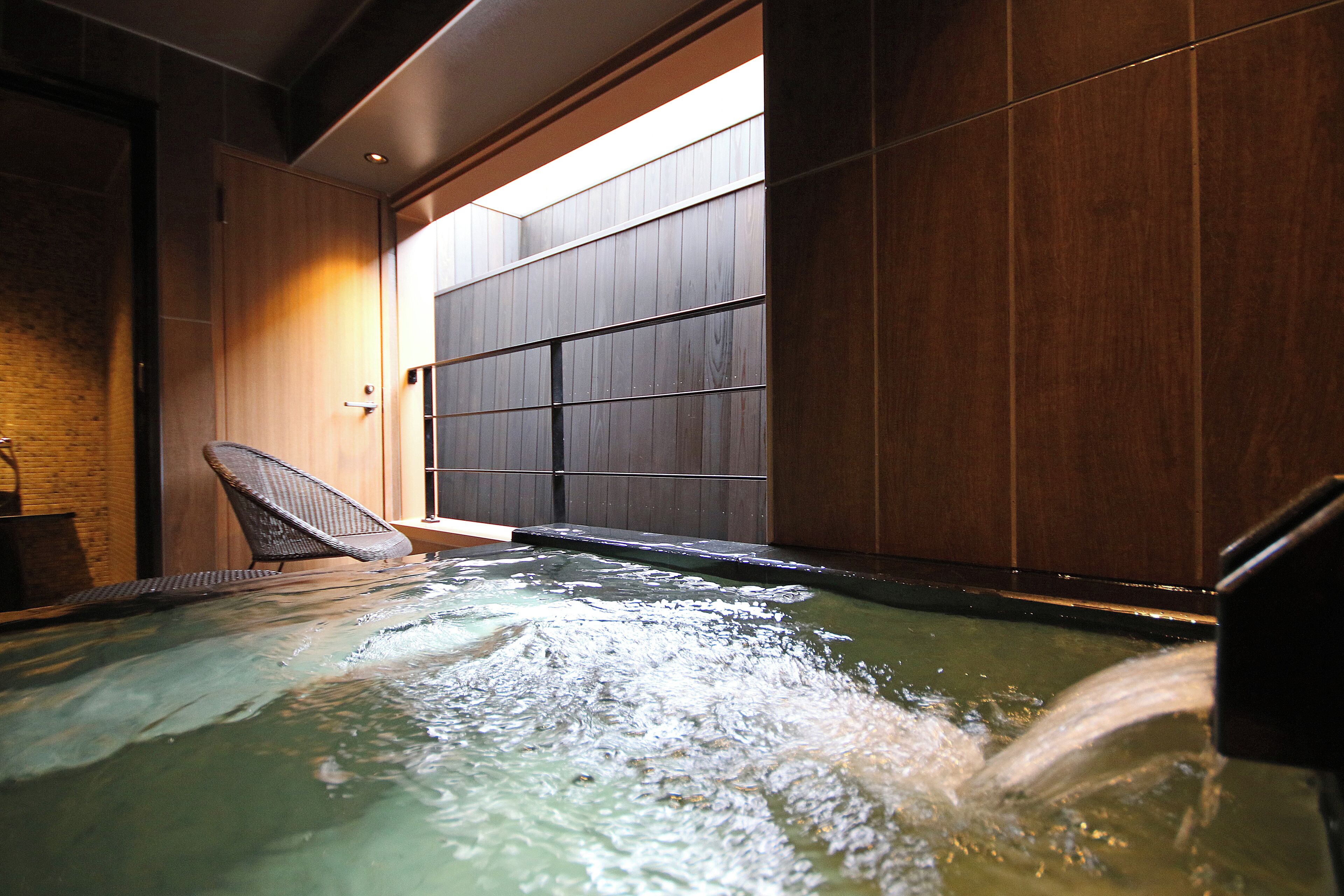 Un bain à remous avec un mur en bois et une chaise.