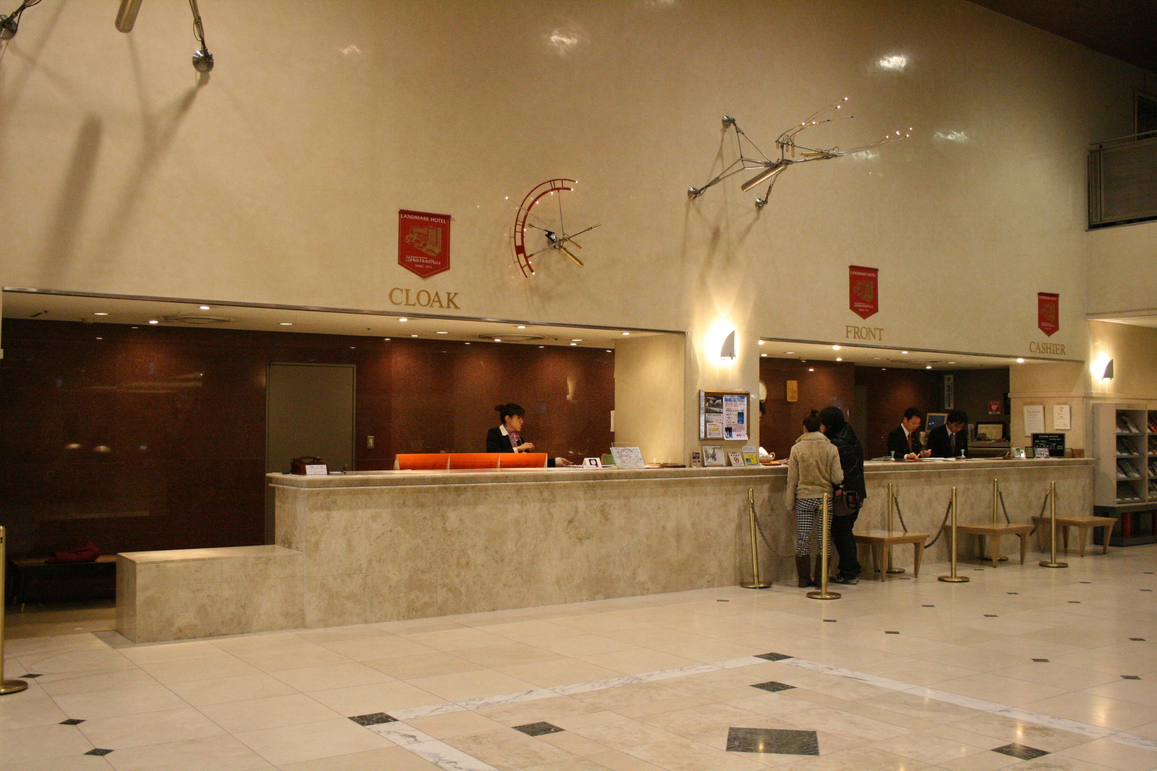 A hotel reception area with a marble floor, a reception desk, and a counter labeled "CLOAK".