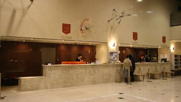 A hotel reception area with a marble floor, a reception desk, and a counter labeled "CLOAK".