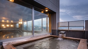 A modern spa area with a hot tub, large windows, and a waterfall feature. - Hida Hotel Plaza (Takayama)
