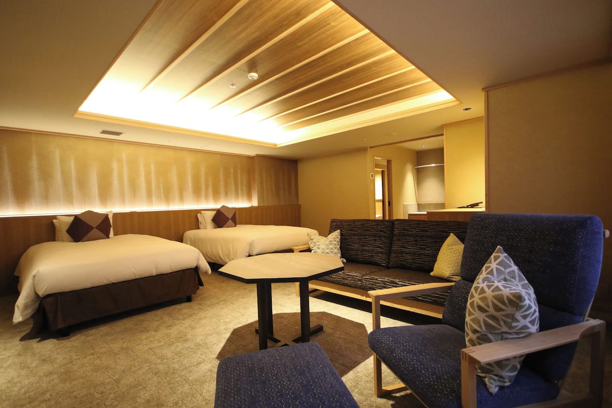 Una habitación de hotel con dos camas, un sofá, una mesita y una silla.
