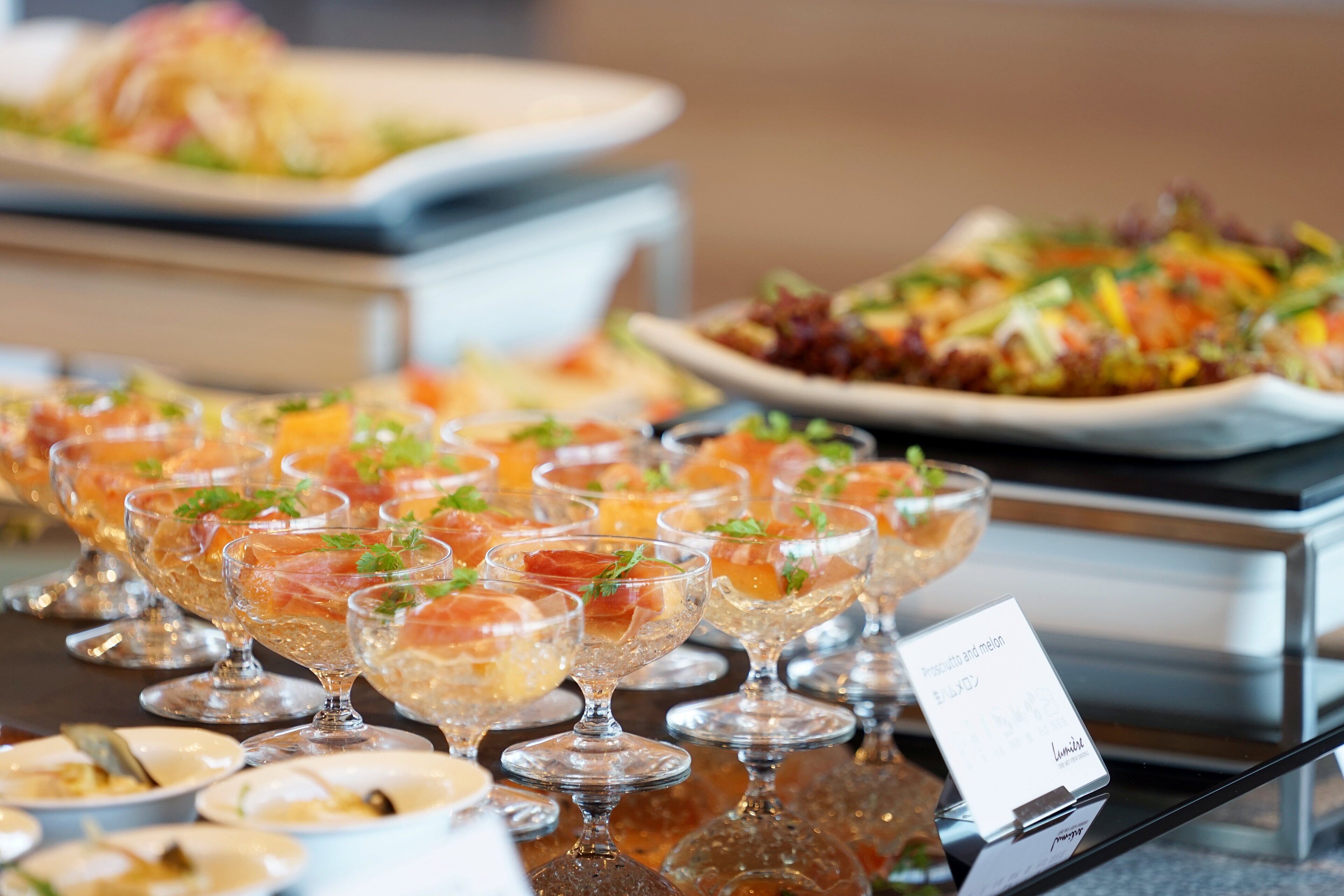 A buffet with various dishes, including a salad and a dish with smoked salmon.