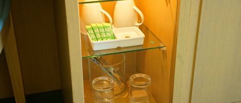 Un mueble con puerta de vidrio que contiene un juego de té y bolsitas de té.