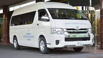 A white van with "Marriott International Hotel Narita" written on the side, parked in front of a building with a glass entrance.