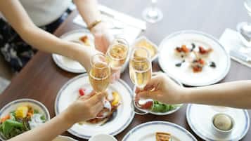Un groupe de personnes trinquant avec des coupes de champagne autour d’une table à dîner où sont servis différents plats.