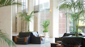A lobby with large windows, modern seating, and potted plants.