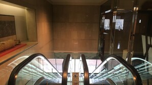 An escalator in a modern building with a tiled floor and glass railings.