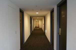 Un largo y estrecho pasillo de hotel con pisos alfombrados y puertas a ambos lados.