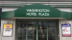 The entrance to Washington Hotel Plaza with a green awning and glass doors.