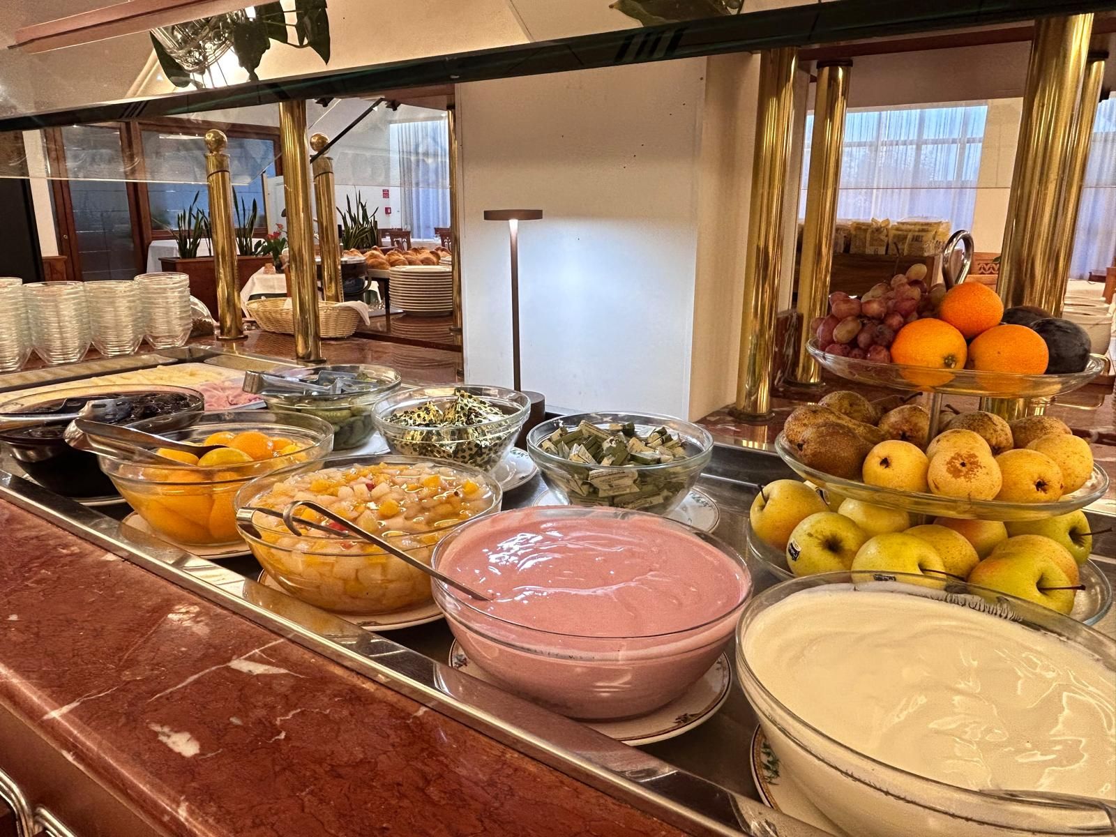 Un bufé con diversas opciones de comida, incluyendo frutas, verduras y salsas.