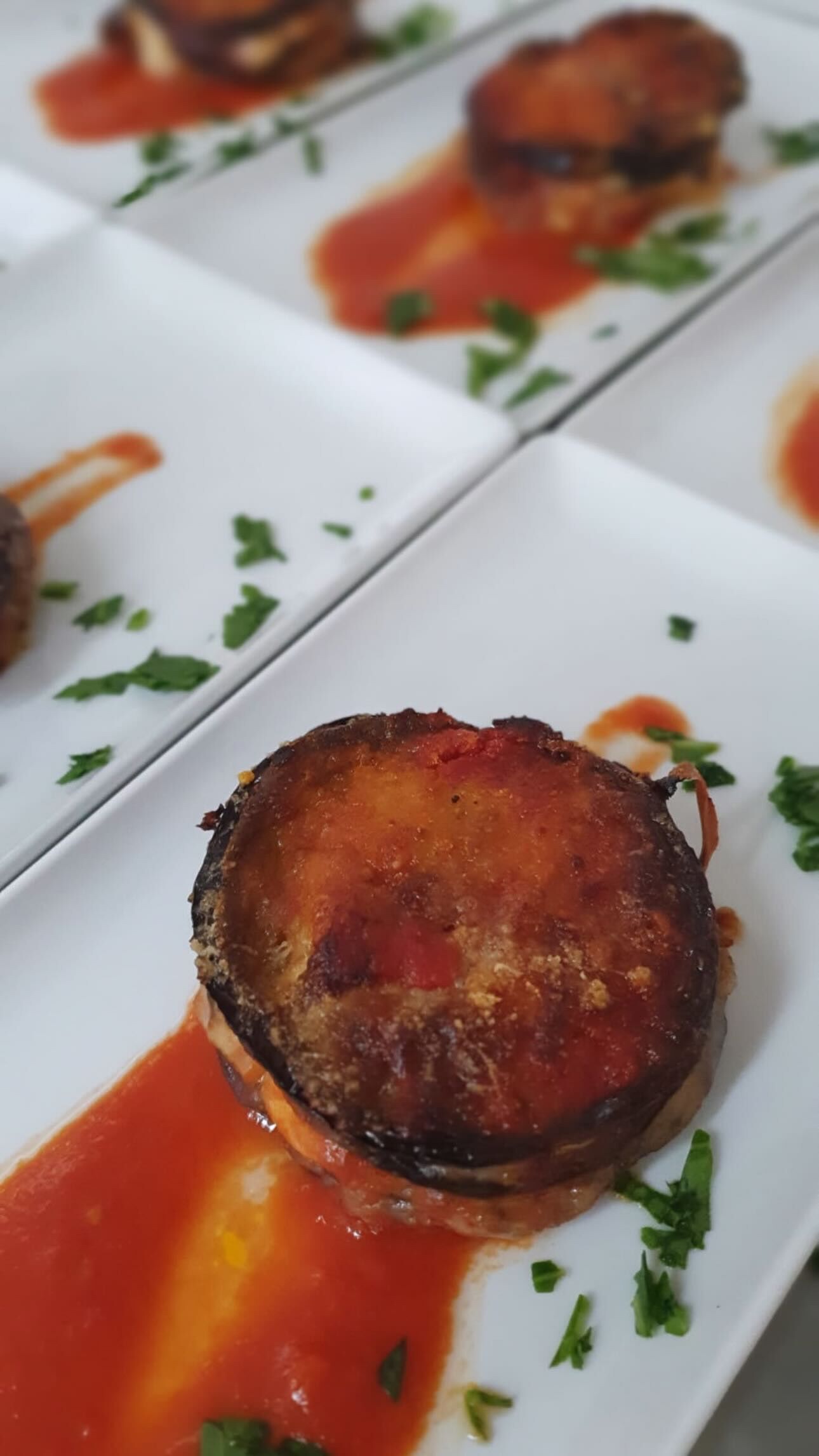 Een bord met een gerecht, versierd met groene kruiden en een rode saus.