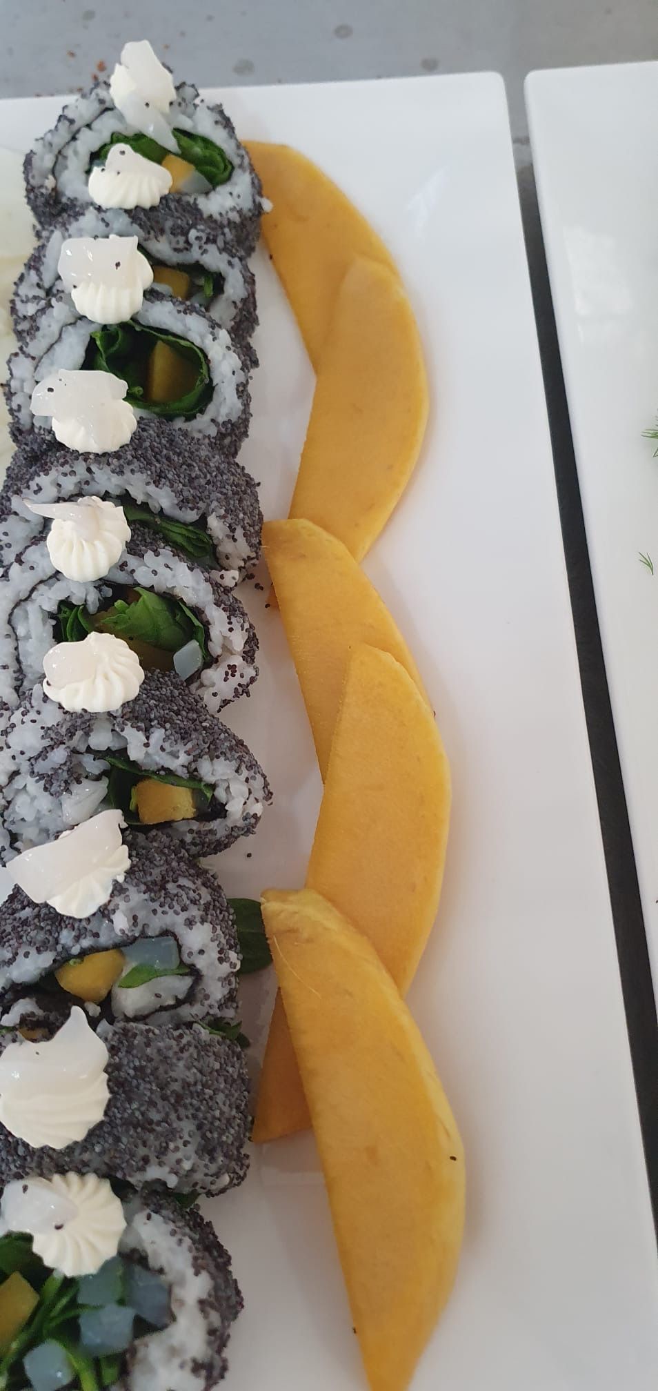 A plate with sushi rolls and mango slices.