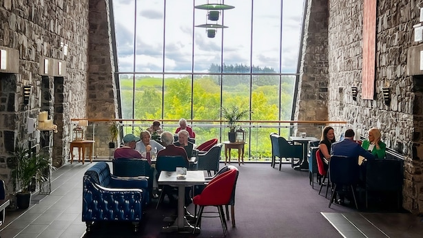 Un restaurante con paredes de piedra, ventanas amplias y mobiliario moderno.