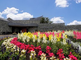 Un hotel con fachada de piedra y un jardín delantero lleno de flores de colores.