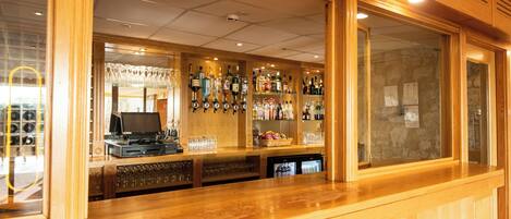 A bar area with wooden counters, shelves of liquor bottles, and a jukebox.