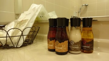 Una encimera de baño con botellas de Jabón Líquido Gold Body, Acondicionador y Champú.