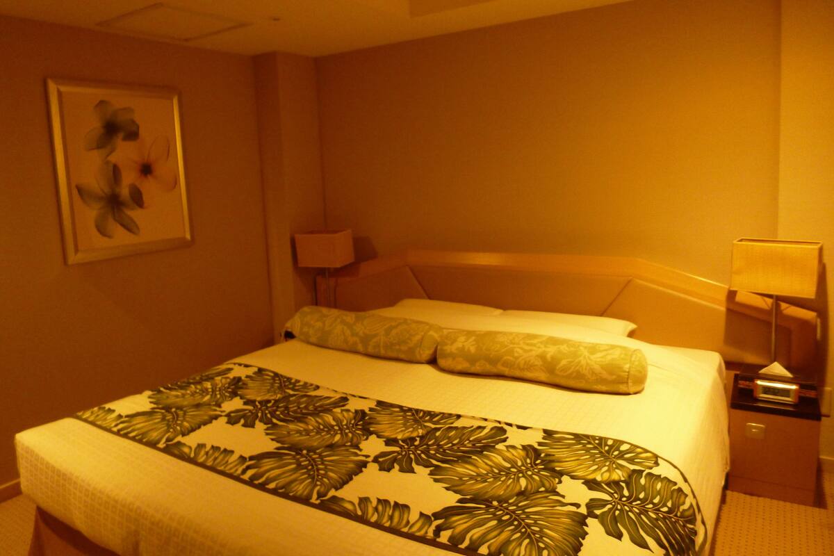 Une chambre d’hôtel avec un lit, une table de chevet, une lampe et un tableau encadré au mur.