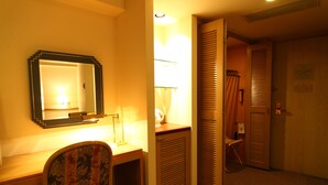 Ein Hotelzimmer mit Schreibtisch, Stuhl, Spiegel und einer Tür zum Badezimmer.