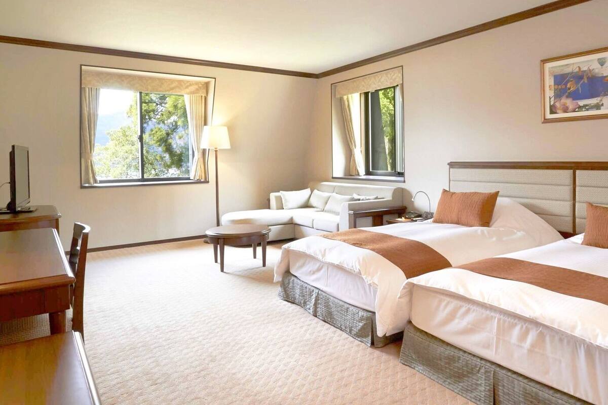 A hotel room with a large bed, a desk, a chair, and a sofa.