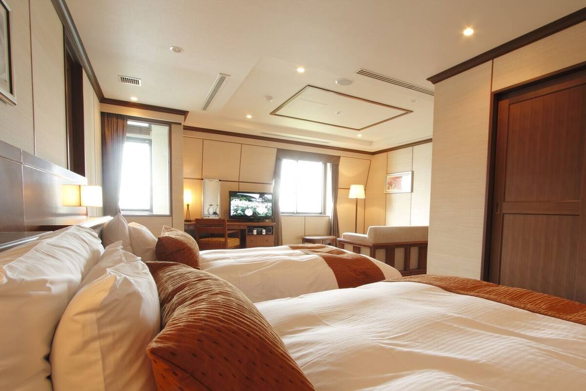 A hotel room with two beds, a television, a desk, and a wardrobe.