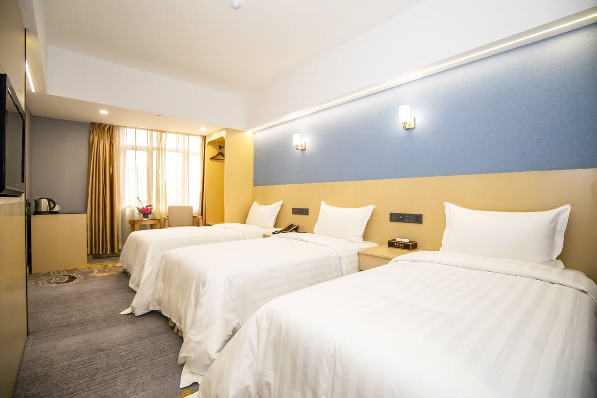 A hotel room with two beds, a desk, a chair, a telephone, and a window with curtains.
