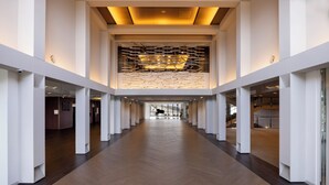 Un corredor moderno de hotel con piso de madera, paredes blancas y un diseño de techo único.