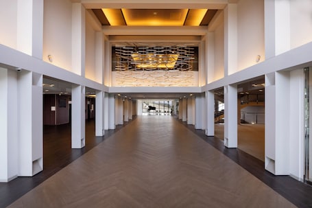 A modern hotel corridor with a wooden floor, white walls, and a unique ceiling design.