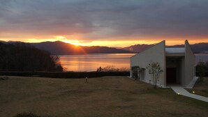 A modern building with a sloped roof near a body of water during sunset. - Mercure Kyoto Miyazu Resort & Spa (Miyazu)