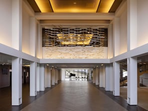 Un intérieur spacieux avec un espace central ouvert, des piliers blancs et un plafond agrémenté d’un luminaire original.