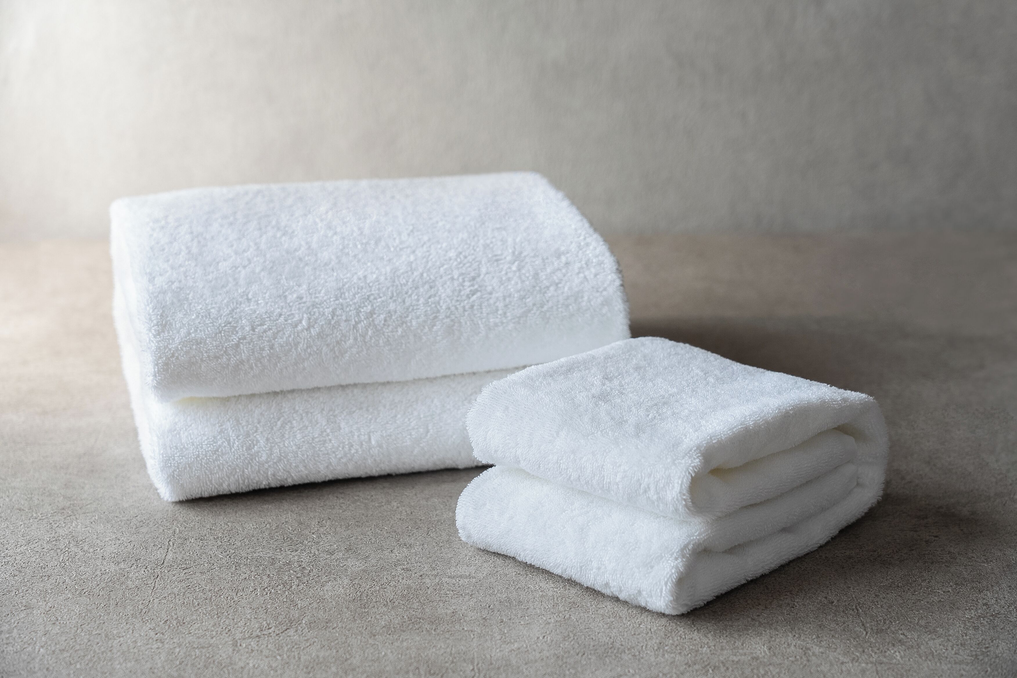 A stack of white towels on a textured surface.