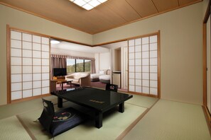 Ein Raum mit Tatami-Matten, einem Tatami-Tisch, einem Futonbett und einer Schiebetür.