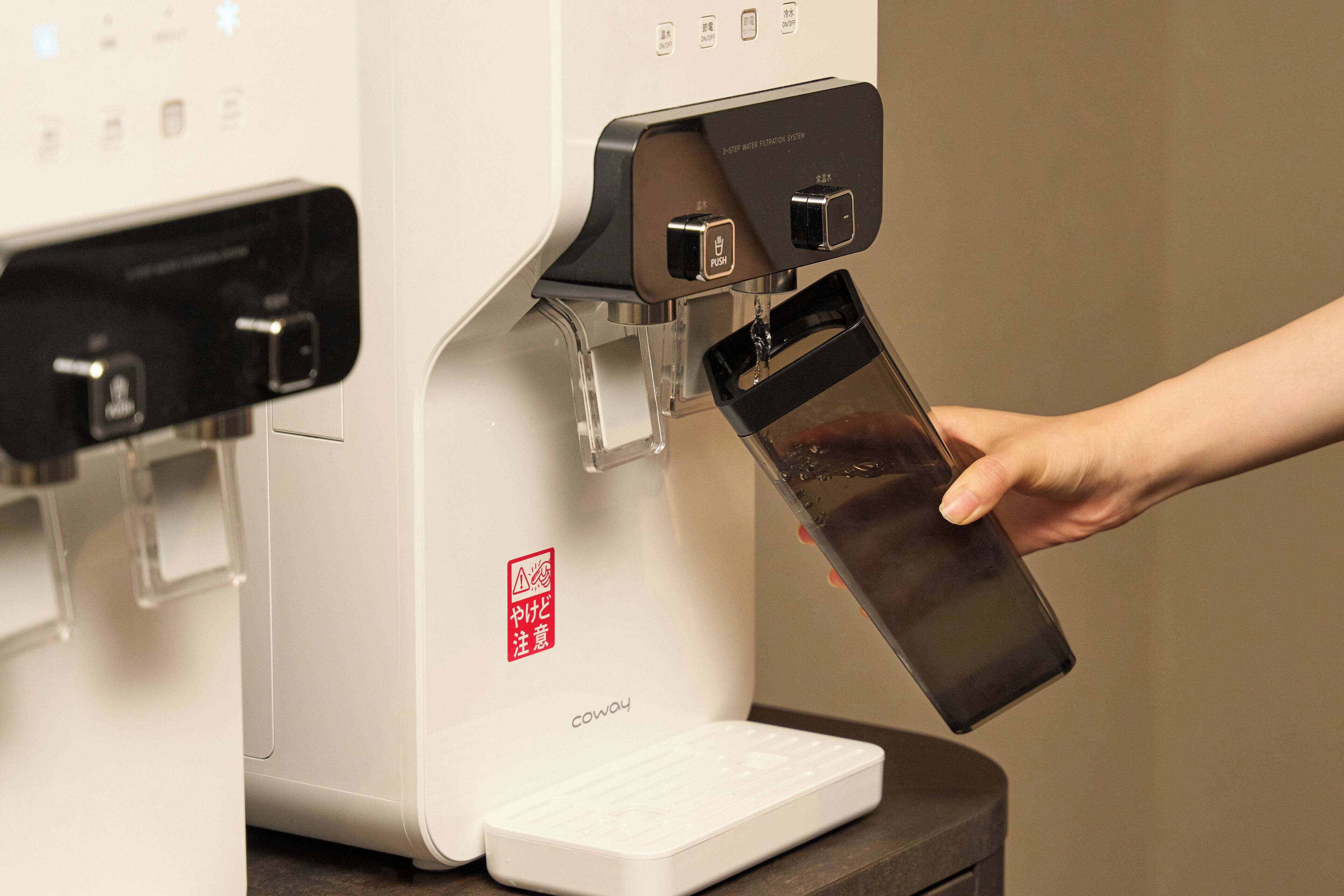 Ein Wasserspender mit Touchscreen-Bedienung und einer Beschriftung 'DRUCKEN'.