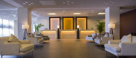A modern lobby with a reception desk, seating area, and a patterned ceiling.